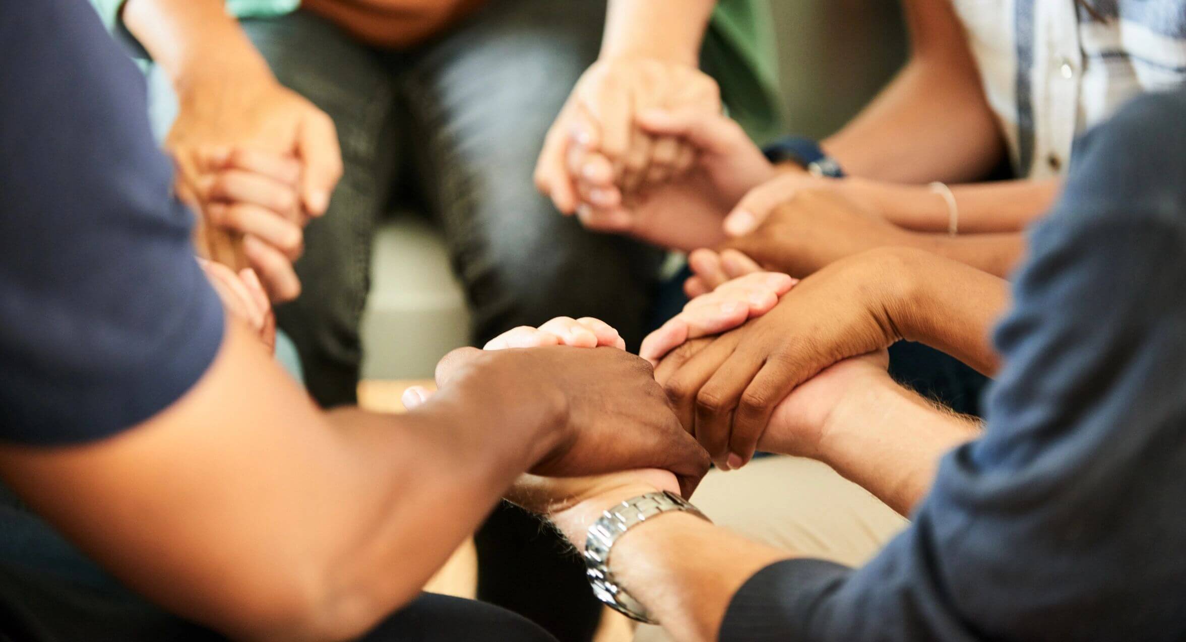 People holding hands in a circle showing unity and support.