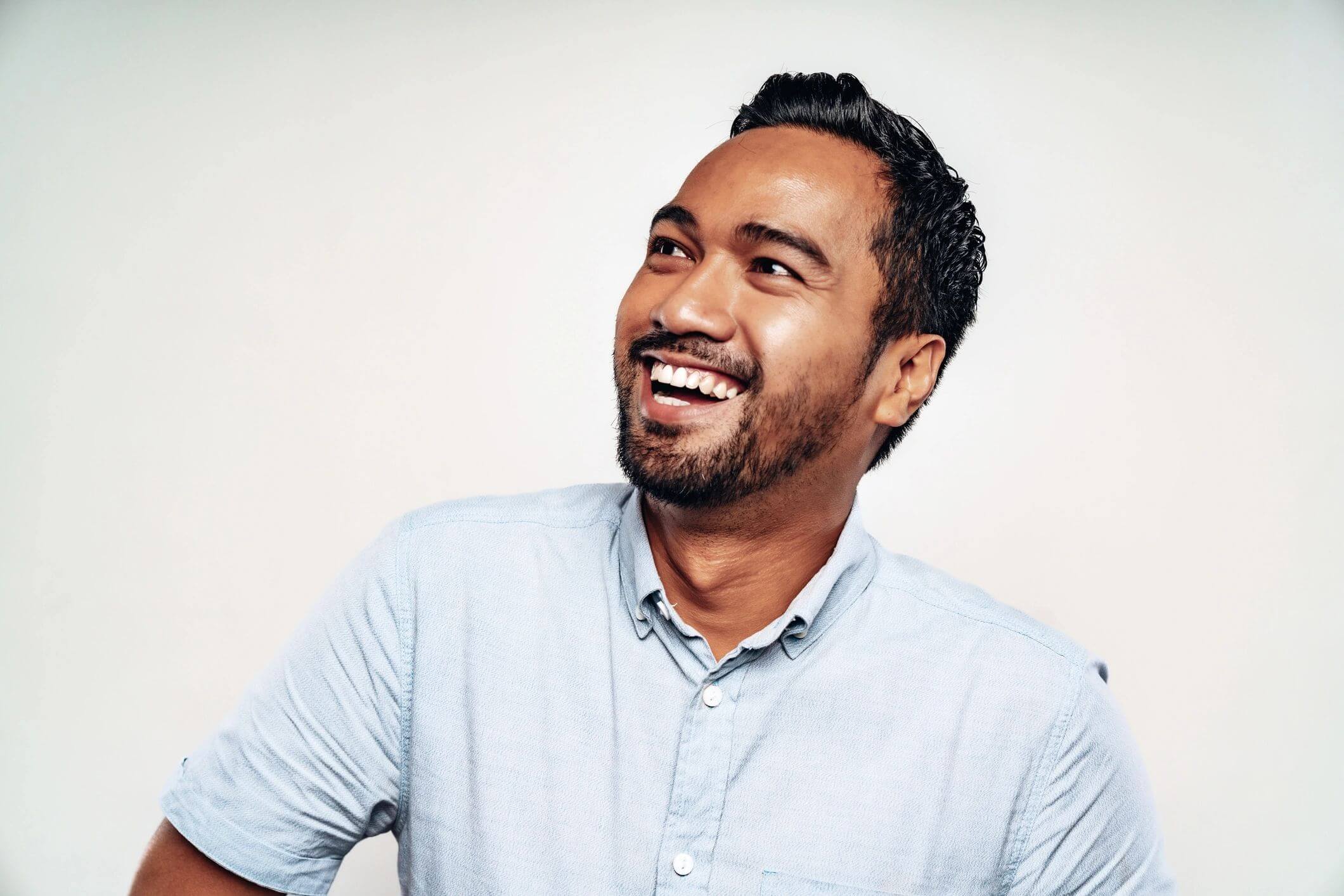 A joyful man smiling and looking to the side.